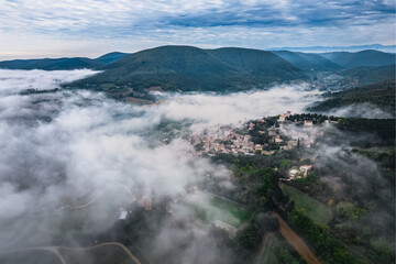 Obraz premium Panoramic view of the old village of Mirmande in France. Aerial photo in the morning in the thick fog rising around the town