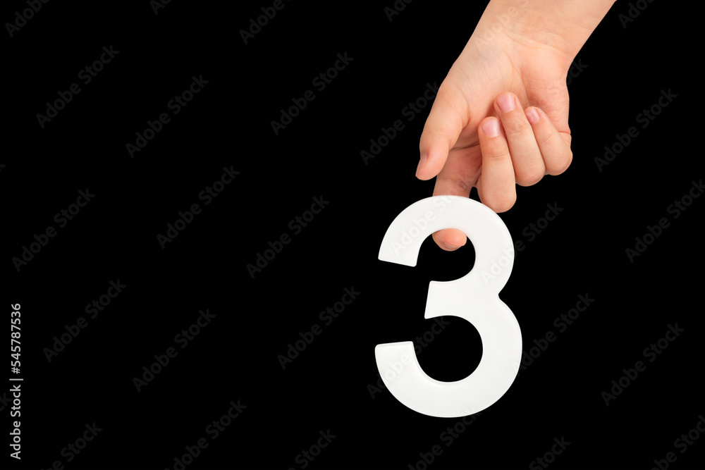 Poster number three in hand isolated on black background. number three in a child's hand on a black backgro