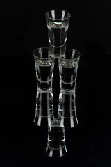 three filled glare glass stacks stand on a reflective surface against a dark background