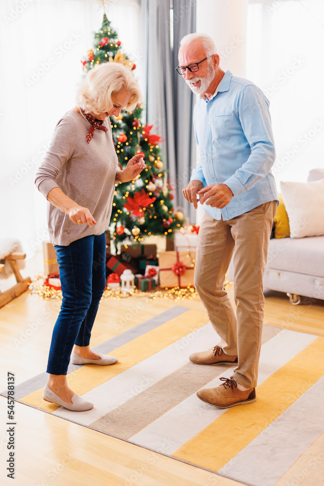 Wall mural Senior couple dancing while celebrating Christmas at home