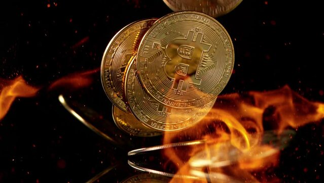 Close up golden bitcoins physical coins falling on black background with fire flames, super slow motion at 1000 fps.