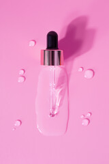 Bottle of drops of anti-aging emulsion and glass pipette on light pink surface close upper view. Skincare and dermatological procedures