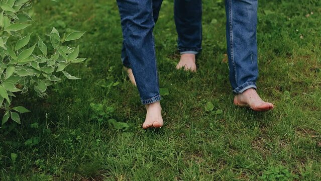 The feet of lovers who walk barefoot on the grass. The camera shoots close-up in slow motion