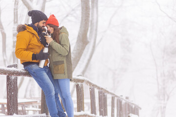 Couple drinking hot tea and relaxing outdoors on snowy winter day