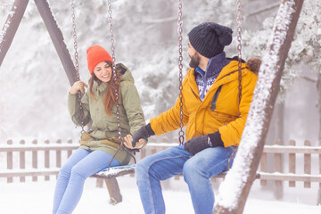Couple having fun swinging outdoors while on winter vacation