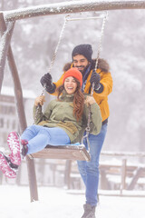 Playful couple swinging while on winter vacation