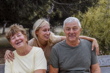 A young woman with elderly parents walks in the park, the concept of family relations