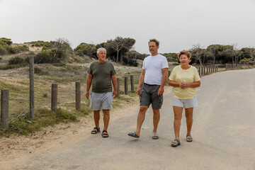 Fototapeta premium Elderly parents with an adult son walk in the park, communication and care for loved ones