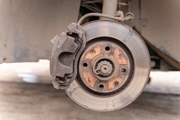 Heavily worn brake disc. Car brake disc after removing the wheel. A rusty disk that needs to be...