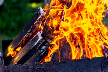 A large fire made of planks. Firewood in a bright flame. Firewood burns brightly in an iron grill.
