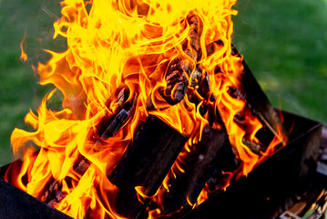 A large fire made of planks. Firewood in a bright flame. Firewood burns brightly in an iron grill.
