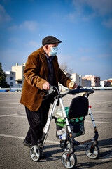 Anciano hombre mayor con su andador, alimentando a las palomas echando de comer a los pájaros con...