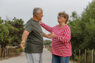 Happy elderly couple embracing in park on sunny day, love together in Valentines day concept, senior couple anniversary