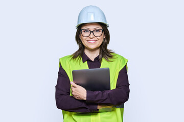 Portrait of engineer manager woman in helmet vest holding laptop