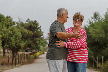 Obraz premium Happy elderly couple embracing in park on sunny day, love together in Valentines day concept, senior couple anniversary