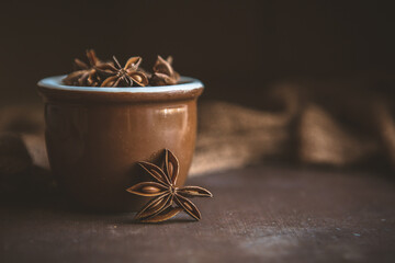 Close up of Star Anise in a Small Brown Bowl on a Brown Background