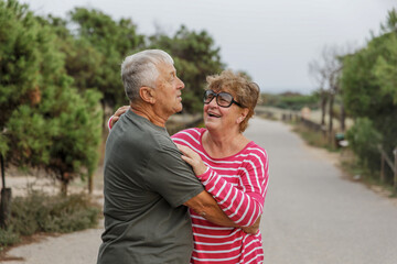 Happy elderly couple embracing in park on sunny day, love together in Valentines day concept, senior couple anniversary