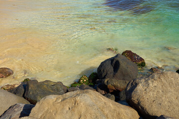 Rocks and waves on a sandy tropical beach.