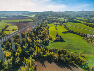 Obraz premium Aerial view of the railroad tracks for high-speed trains on the flyover. Panoramic autumn view of the surrounding fields and forests and the surrounding mountains.