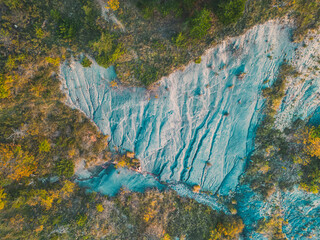 Black ground autumn landscape on a mountain slope in the alps. Panoramic landscape of the valley during the setting sun. Limestone rocks covered with trees in autumn colors