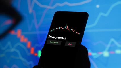 Un inversor está analizando el indonesia etf fondo en pantalla. Un teléfono muestra los precios...