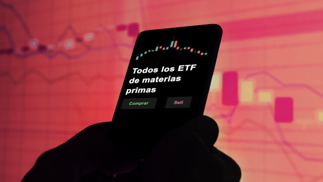 Un inversor est&aacute; analizando el todos los materias primas etf fondo en pantalla. Un tel&eacute;fono muestra los precios del ETF para invertir. Texto en espa&ntilde;ol.