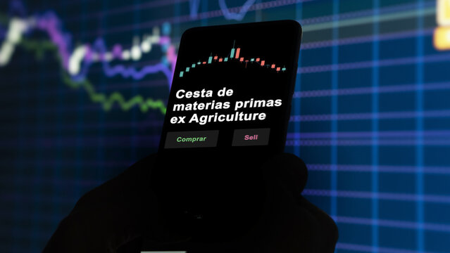 Un inversor est&aacute; analizando el cesta materias primas ex agriculture etf fondo en pantalla. Un tel&eacute;fono muestra los precios del ETF para invertir. Texto en espa&ntilde;ol.