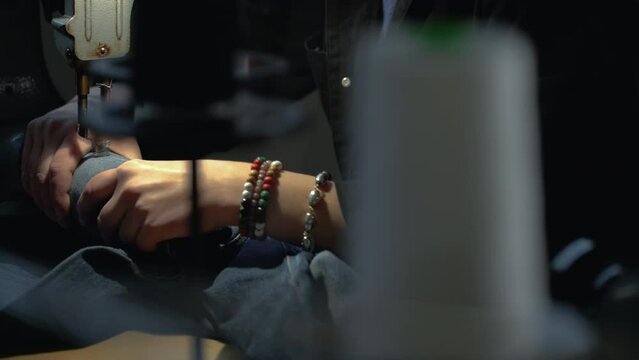 A female tailor seamstress repair old jeans with vintage darning machine in a workshop repairing denim clothes. Small family business, tailoring and repair of clothes, handmade, startup. Close-up