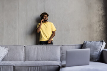 Young indian man talking on the phone while sitting on a couch