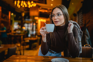 One woman young adult caucasian female sit at cafe alone having a cup of coffee while wait