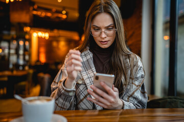 One woman young adult caucasian female sit at cafe alone using mobile phone for online internet browsing or text messages and social network copy space