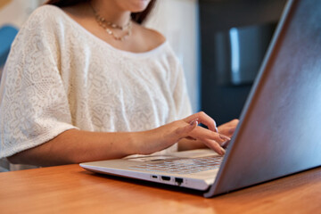 close up of a young woman's hands working on a laptop in a coworking space, selective approach