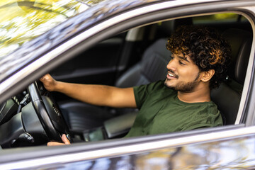 Young handsome indian man proudly driving his car