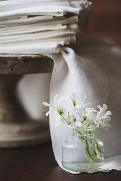 Stack of Clean White Napkins on a Pedestal with Small Vase of White Flowers