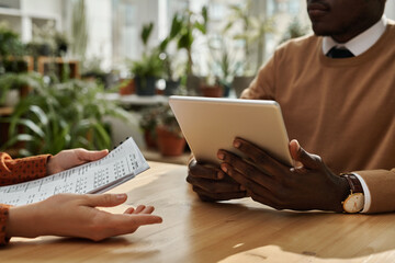 Close-up of colleagues using digital tablet and discussing business strategy together at meeting