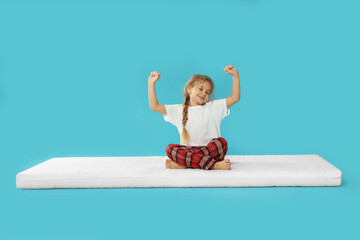 Little girl waking up on mattress against light blue background