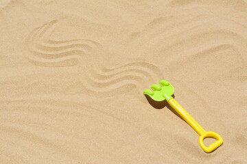 Fototapeta na wymiar Plastic rake on sand, space for text. Beach toy