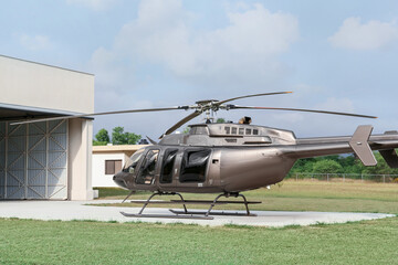 Beautiful helicopter on helipad in field near hangar - obrazy, fototapety, plakaty