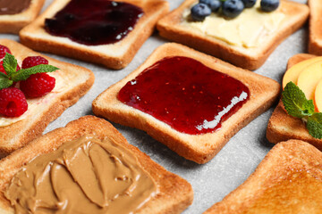 Tasty toasts with different spreads and fruits on light grey table, closeup