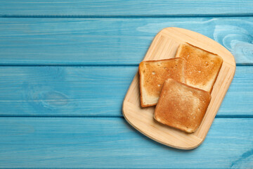 Slices of tasty toasted bread on turquoise wooden table, top view. Space for text
