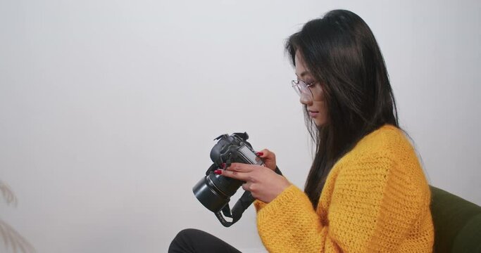 asian woman chooses photos on camera on white background