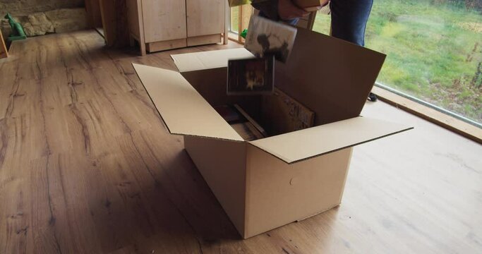 Put books in cardboard box , prepare for the move , Medium shot