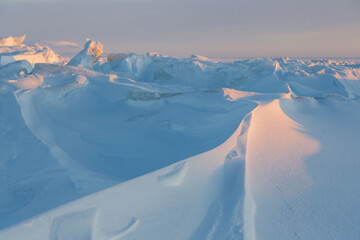 Winter arctic landscape. Ice hummocks on the frozen sea in the Arctic. View of snow and ice at sunset. Cold frosty winter weather. Harsh polar climate. Amazing nature in the far north in the Arctic.