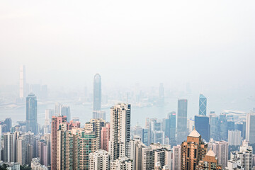 Fototapeta na wymiar Aerial view of Victoria Harbour, Hong Kong skyline and parts of Tsim Tsa Tsui as seen from the Peak on a hazy day; Hong Kong Island, China
