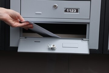 Woman taking envelopes out from mailbox indoors, closeup