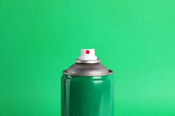 Colorful can of spray paint on green background, closeup