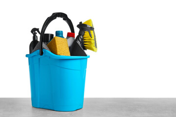 Bucket with many different car wash products on grey table against white background