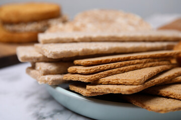 Rye crispbreads, rice cakes and rusks on white marble table, closeup