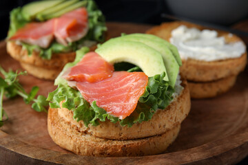 organic rusks with salmon, cream cheese and avocado served on wooden board, closeup
