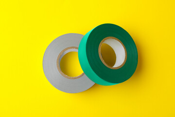 Colorful insulating tapes on yellow background, flat lay